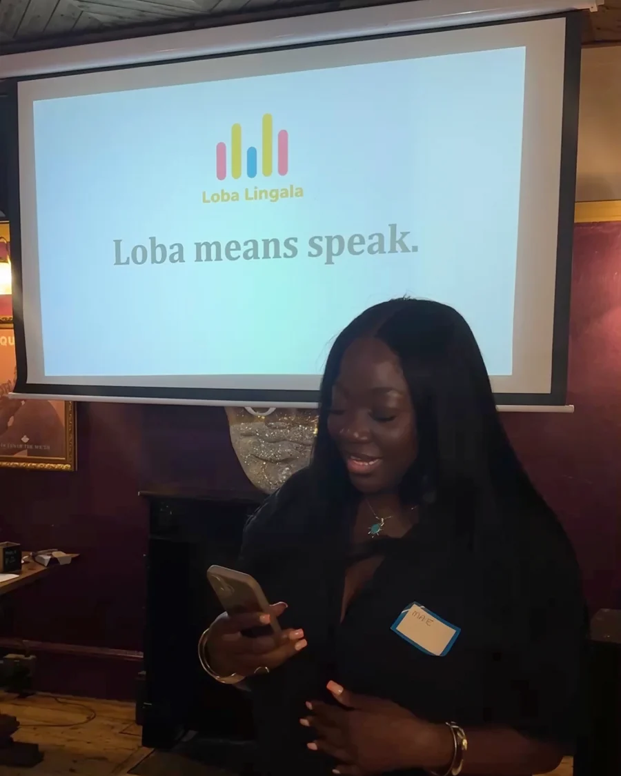 Maïté, founder of Loba Lingala, at our first event, under a screen that reads “Loba means speak.”